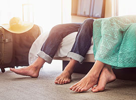 A close-up of a husband and wife's bare feet on the floor of their hotel room.