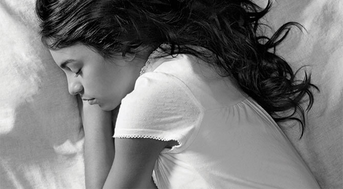 A young girl asleep in bed.